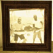 A picture of Warner on a fishing boat holding a fish with Hawthorne.