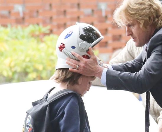 August's father helps him with his helmet