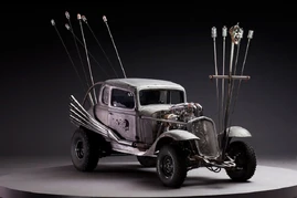 Transitional version of Nux's car, bare metal with skull design on the door.