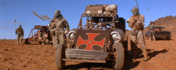 Smegma Crazies beside a vehicle with an iron-cross decal