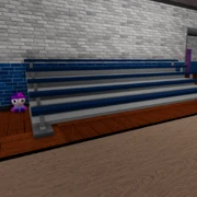 In the wrench room in school, beside a bleacher