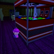 Behind claw machine in the green room.