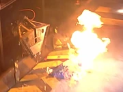 M2 flips Vader out of the arena while being doused in flames.