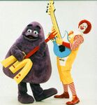 Grimace & Ronald McDonald playing the electric guitar.