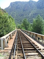 La voie du Train Jaune au niveau du PN1 (entrée dans Villefranche), vue en direction de la gare, avec le viaduc métallique le long de la Têt (Août 2006)