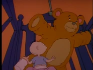...and his enlarged teddy bear trying to flatten him