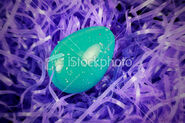 Green easter egg laying in purple grass