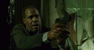 Tapp holds Jigsaw at gunpoint