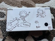 A white Nintendo DSi system featuring Scribblenauts artwork drawn on it, awarded as a contest prize at PAX during an unknown year