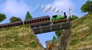 A green saddle tank engine resembling Percy from Thomas & Friends. The bridge also makes a resemblance to The Valley Bridge from Thomas & Friends