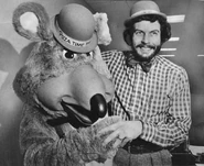 Nolan Bushnell posing with the Chuck E. Cheese walkaround character.