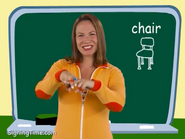 Chair. Make your fingers sit on the chair. Tap it for ‘chair.’ Leave them sitting for ‘sit.’ Chair.