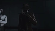 The Detective Cameraman using 2 fingers and pointing at himself.