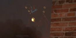 The infected Titan Speakerman visible through the smoke and fog atop a building, staring at  (POV).