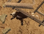 Под обломками, тянет руку.