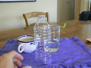 The tools used for the longevity test. A coffee cup with 1 teaspoon of bubble juice. A plastic bottle whose bottom has been removed. A jar into which the water bottle is placed.