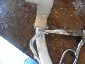 Choose the cord that you will use to wrap your hoop with. Shown here is Rubbermaid rayon mop head yarn. Tie one end of the cord/yarn into a knot and begin stuffing the knotted end into the hole you drilled.