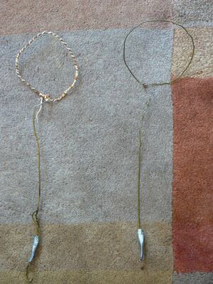 Two homemade bubble wands made by bending wire coat hangers into shape. The loop of the wand on the left s wrapped with cotton twine which enables it to hold more bubble juice and hence make larger bubbles or more bubbles than a non-absorbent wand.