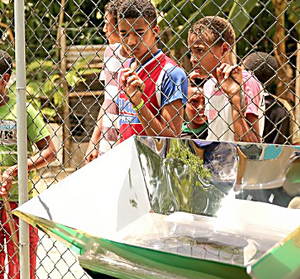 Children wait for a solar cooked meal to finish cooking
