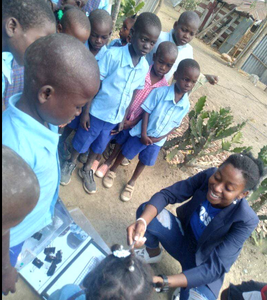 Aline Innocent displays the cooked rice to the curious children