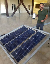 Amir holds a coffeemaker that he reports boils water with energy generated with the accompanying PV panels - Photo credit: Amir Komarizade]]