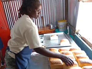 Solar baking trainee removes the fresh loaves, Photo credit: Lytefire
