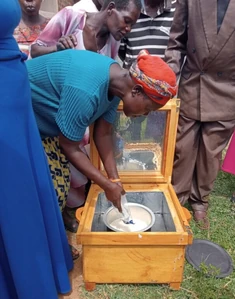 Adding food in a solar box cooker at a COMPE demonstration