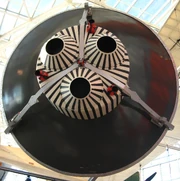 The aft end of a mock Mercury Capsule, showing the red posigrade nozzles and the three main nozzles on the retro pack.