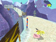 Screenshot of SpongeBob, sliding down the Sand Mountain with an early version of the HUD and of the Thunder Tiki.