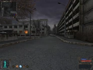 Down this street, past the car to the gate on the left by the truck.