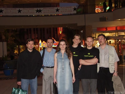 Слева от центра, в полосатой рубашке