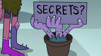 S2E1 Potted hand-plant with 'Secrets?' sign