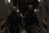Stan Kovacek walking with Hammond in corridor at level 28