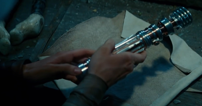 Rey holding the lightsaber on Ahch-To