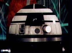 An R2 astromech droid with a white dome and dark green body