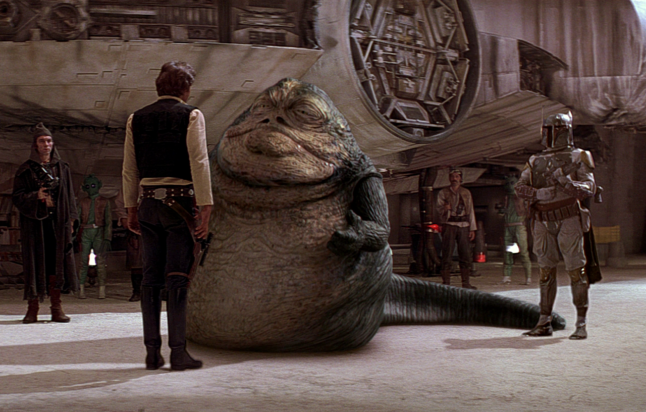 Boba looks on as Jabba the Hutt speaks to Han Solo in Mos Eisley.