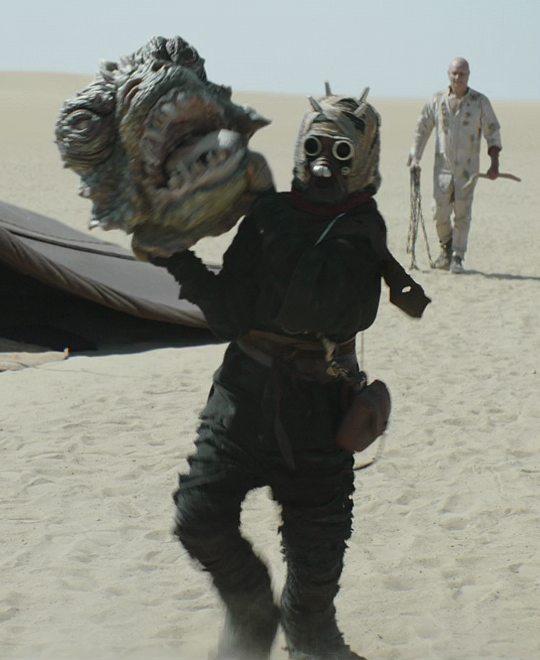 The youngling carrying the sand creature's head in triumph