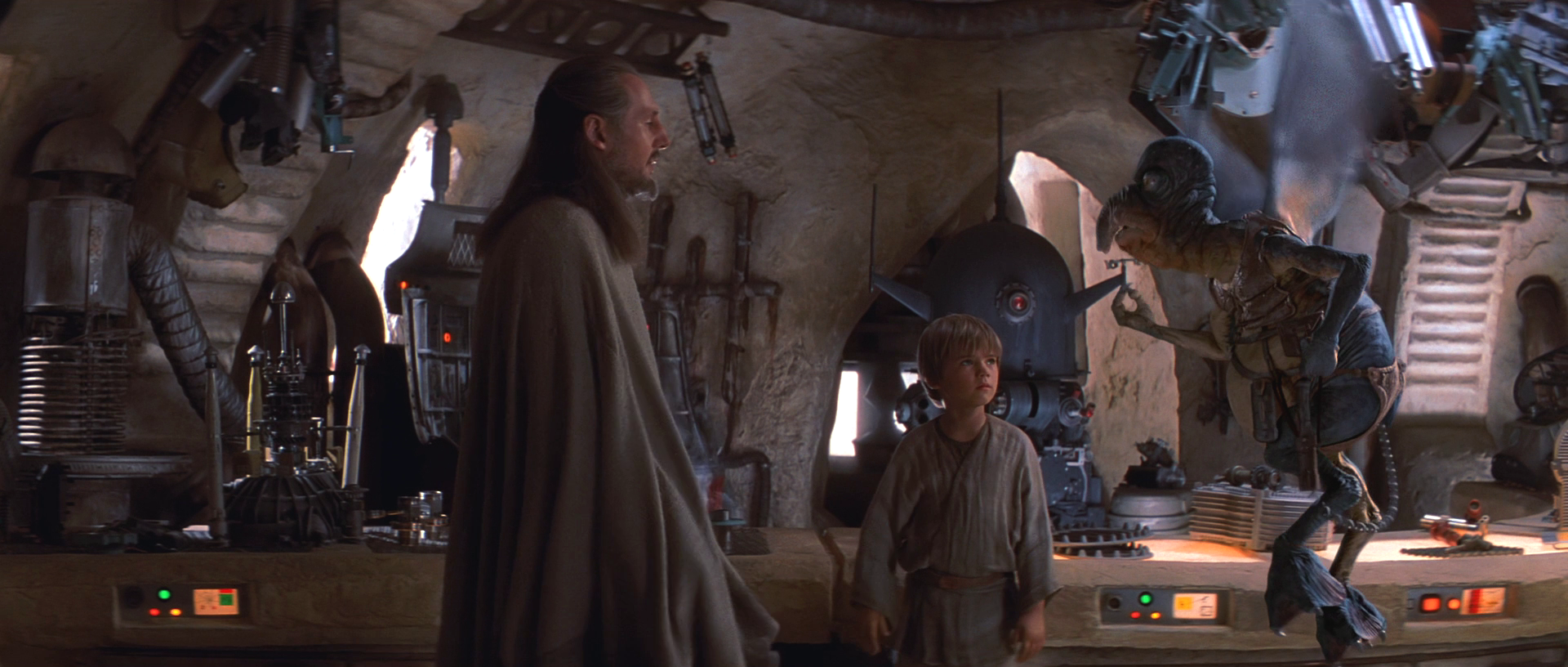 Qui-Gon Jinn negotiates with Watto as Anakin Skywalker looks on