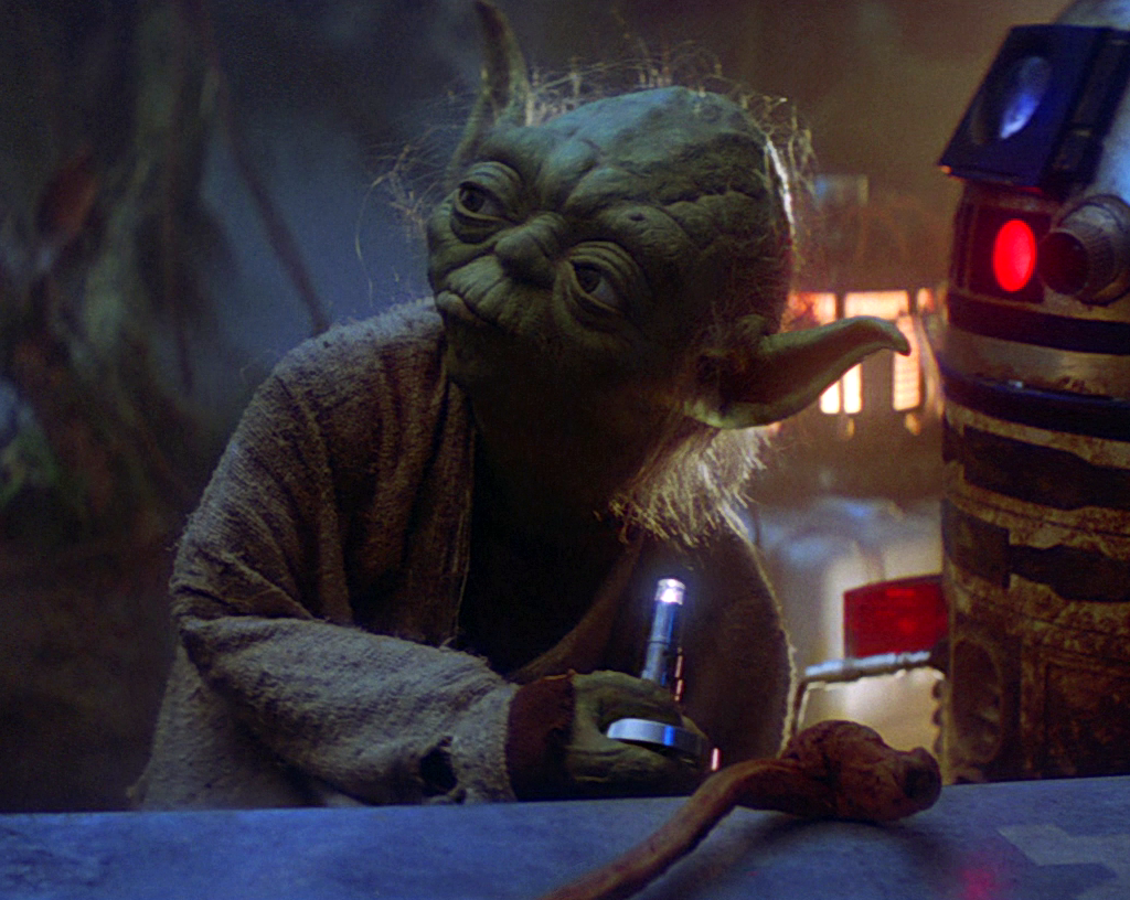 Yoda holds a small lamp.