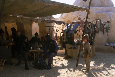Quinlan Vos seduto al tavolo di una taverna mentre passa Anakin Skywalker