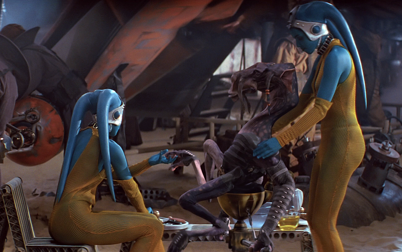 Sebulba receives a massage from his twin Twi'lek slaves prior to the race.