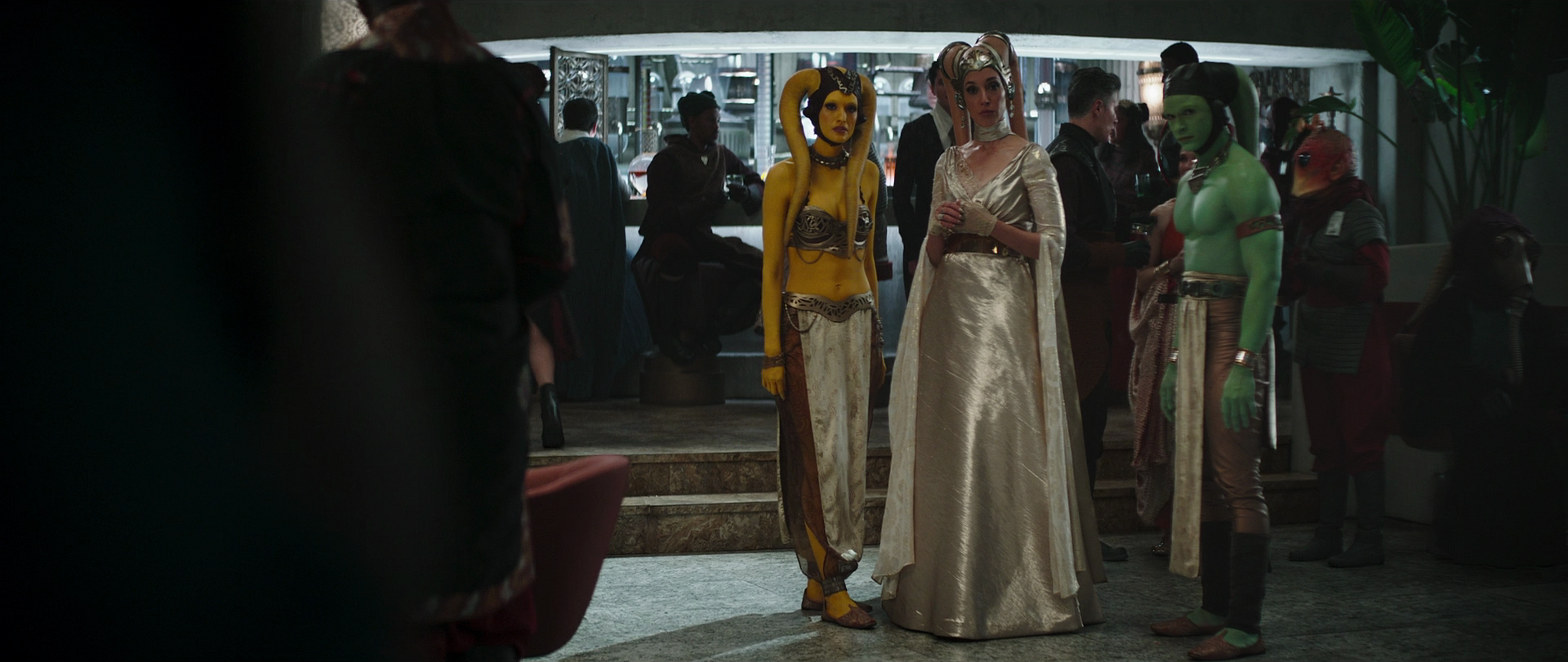 The Twi'lek stands beside Fwip and male colleague as the Pykes depart.