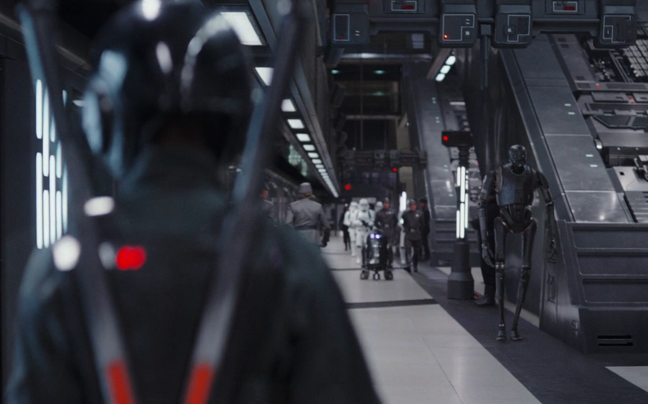 C2-B5 approaches Jyn Erso, a rebel infiltrator disguised in an Imperial ground crew uniform.