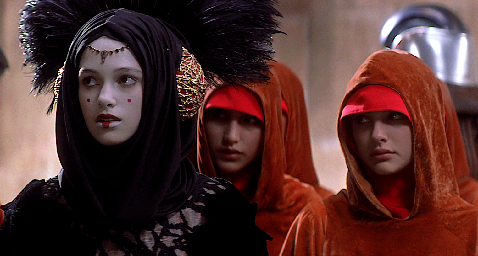 The handmaiden Sabé is disguised as the sovereign while Queen Amidala is dressed as a handmaiden to Sabé's left.