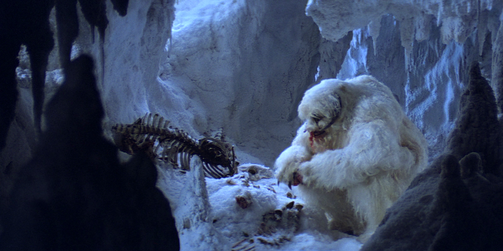 A wampa feasts on a tauntaun in its cave.