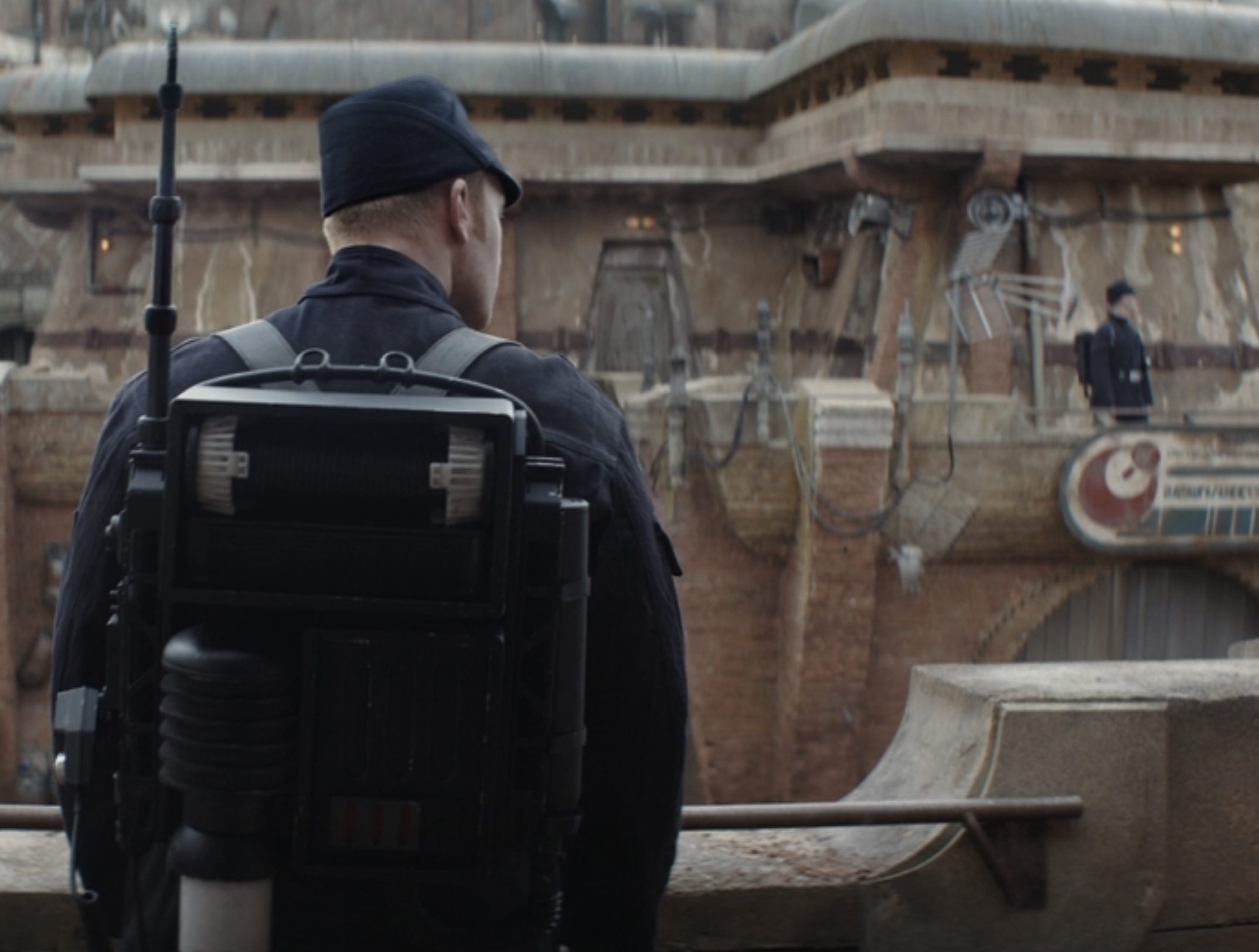 An Imperial security trooper with a communications pack overlooks the procession on Rix Road.