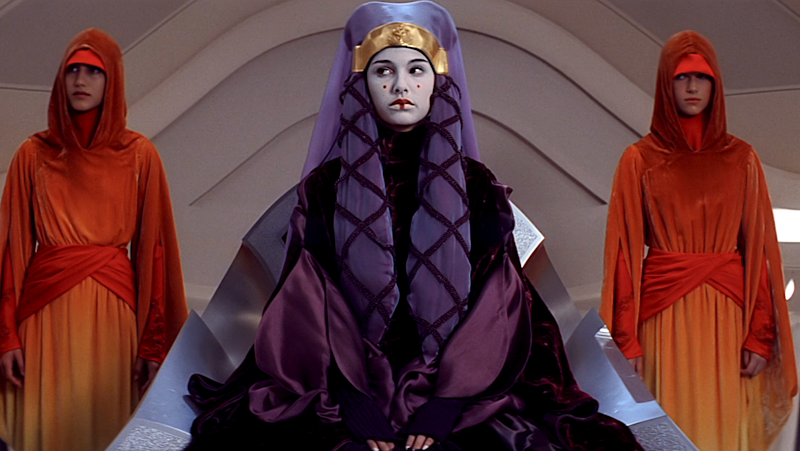 Sabé and Rabé wear flame-colored robes while attending the queen of Naboo.