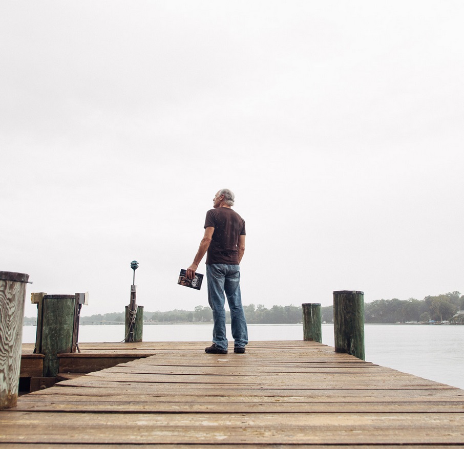 Luceno gazes at the river near his log cabin home. Image © 2016 Allison Zaucha