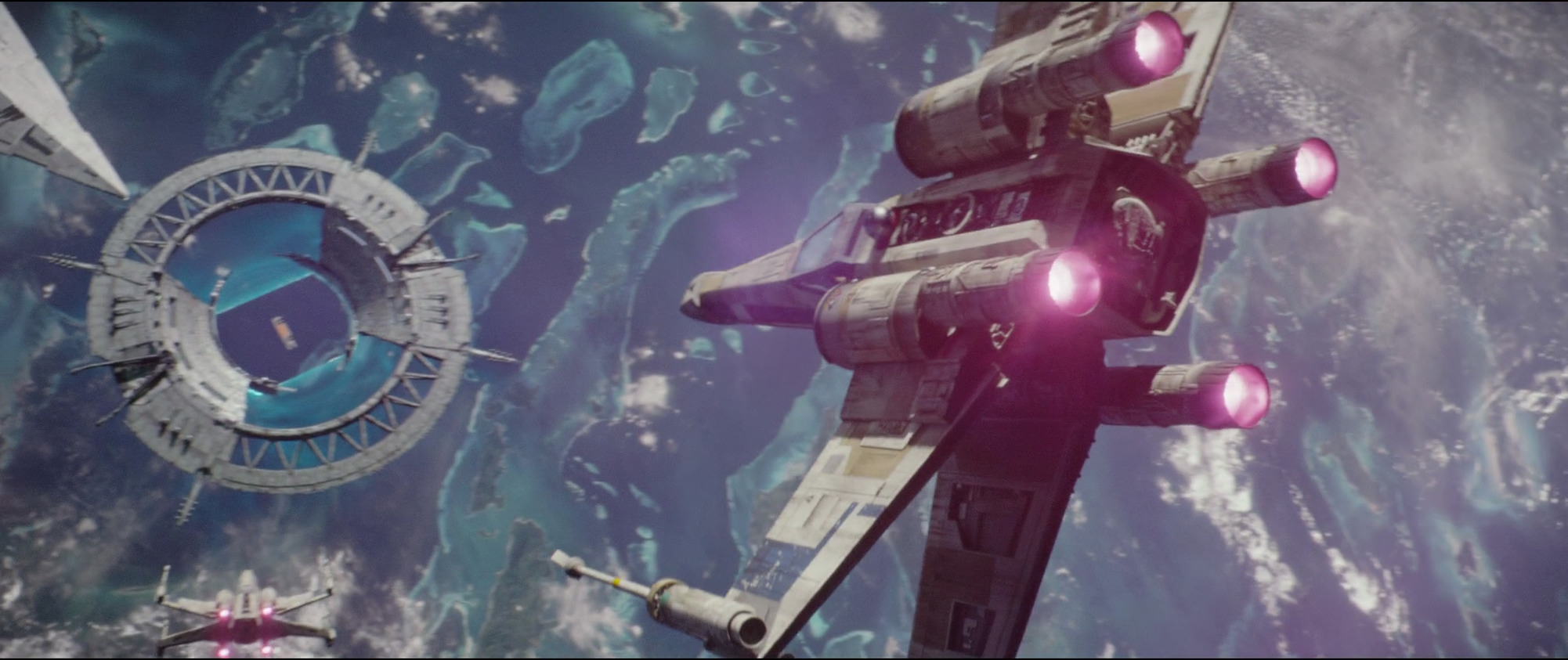 A T-65 X-wing piloted by Antoc Merrick attacks the Scarif Shield Gate.