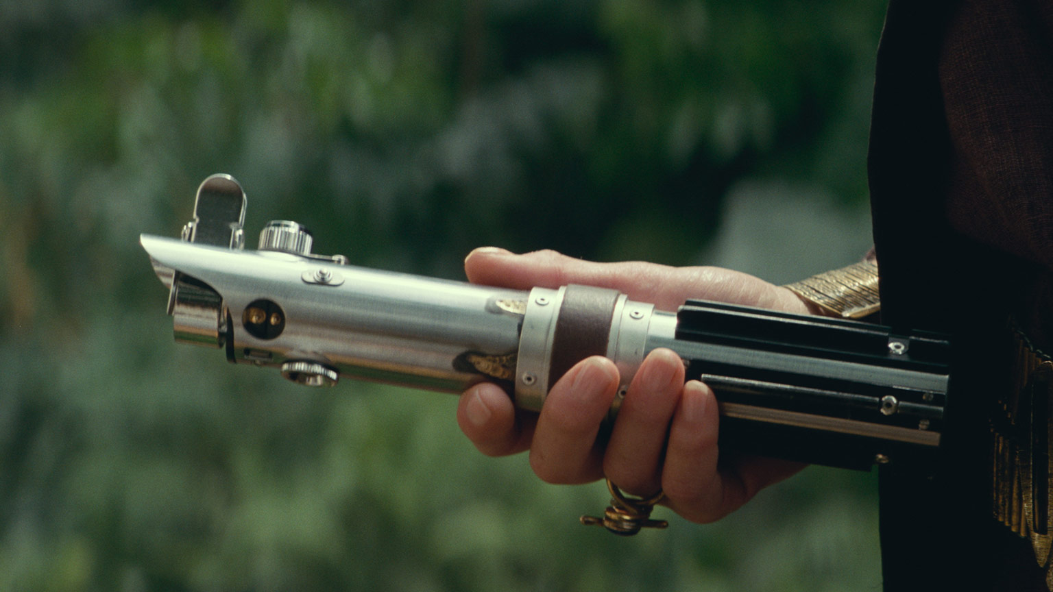 Leia holding the lightsaber of her father, brother, and apprentice.